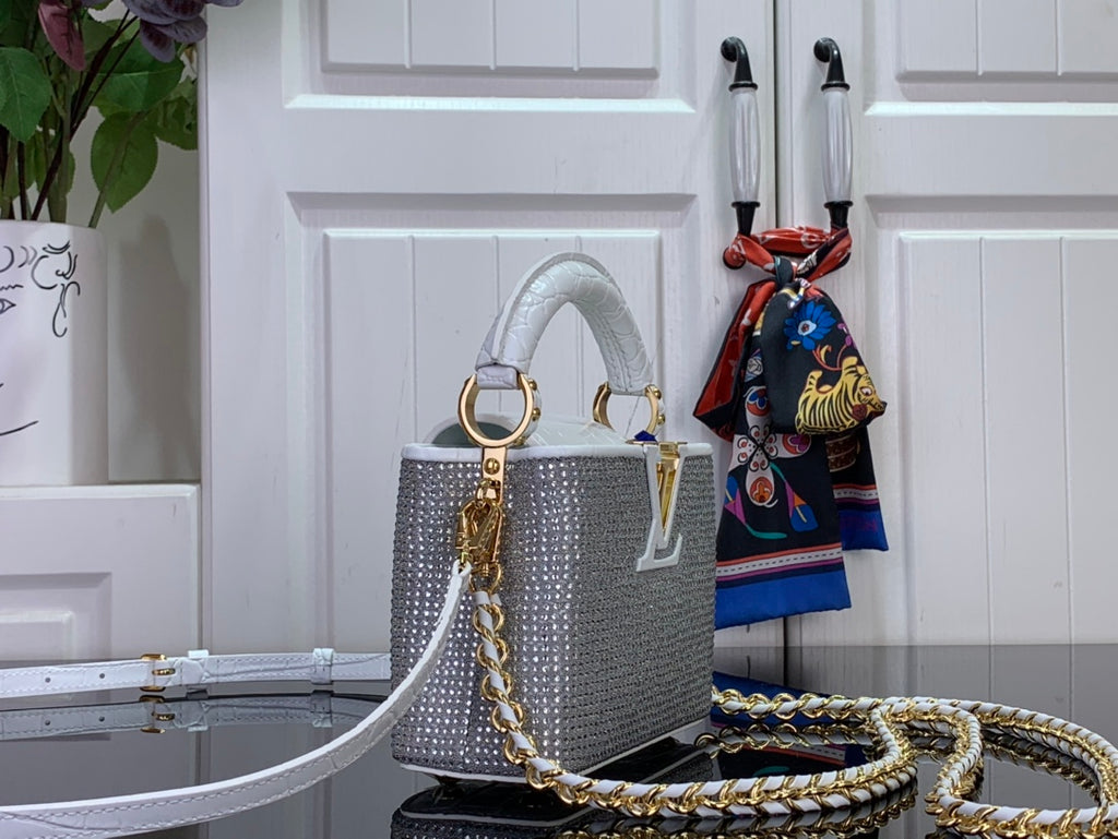 White handbag with structured body, gold hardware, chain shoulder strap