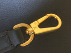 Gold lobster clasp on a black leather strap of the bag