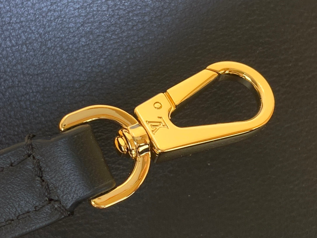 Gold lobster clasp on a black leather strap of the bag