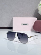 MiuMiu sunglasses with dark blue lenses and gold-tone metal frame, pointed cat-eye shape
