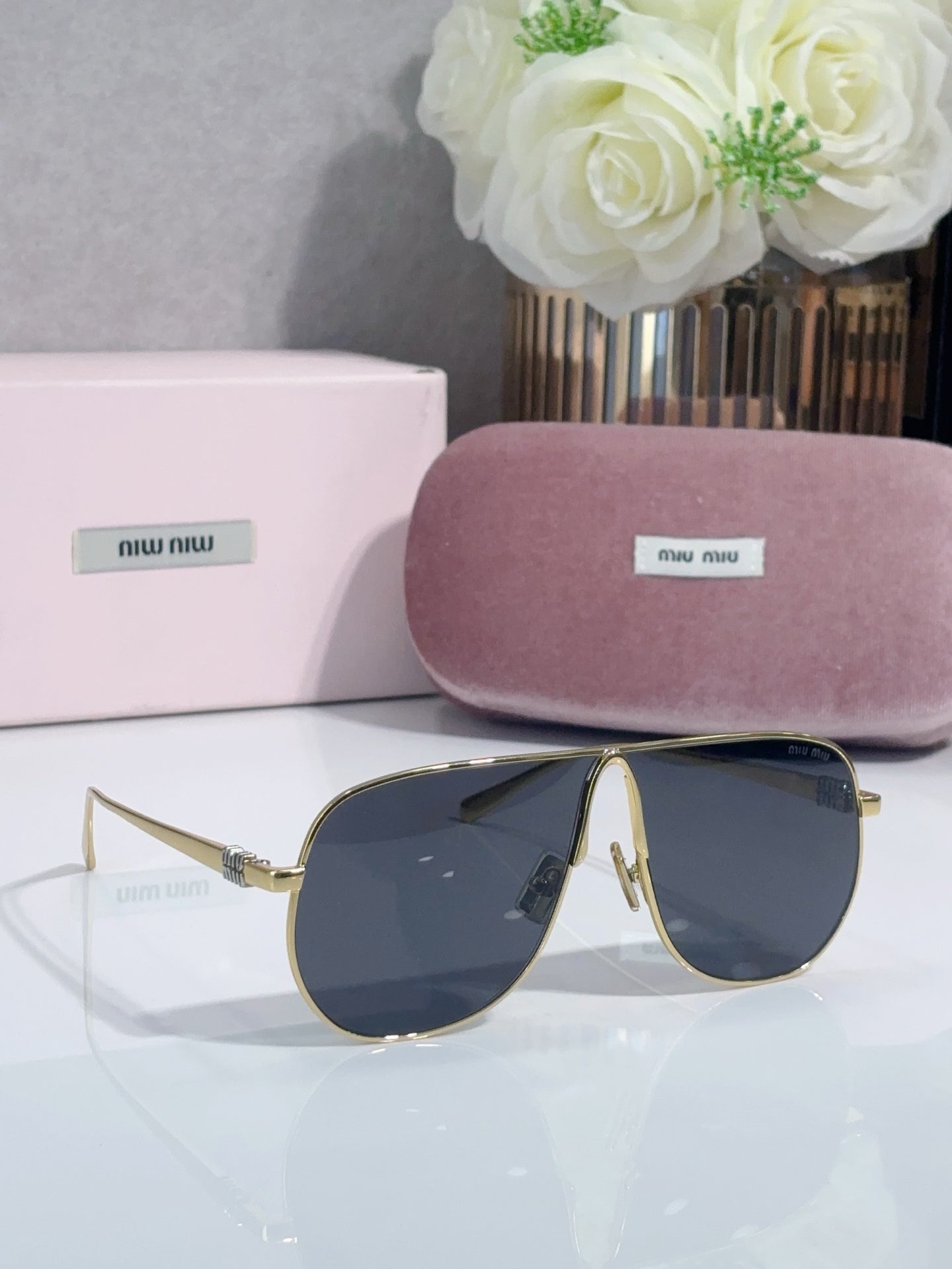 Gold-tone sunglasses with dark blue lenses, curved frame and pointed tips