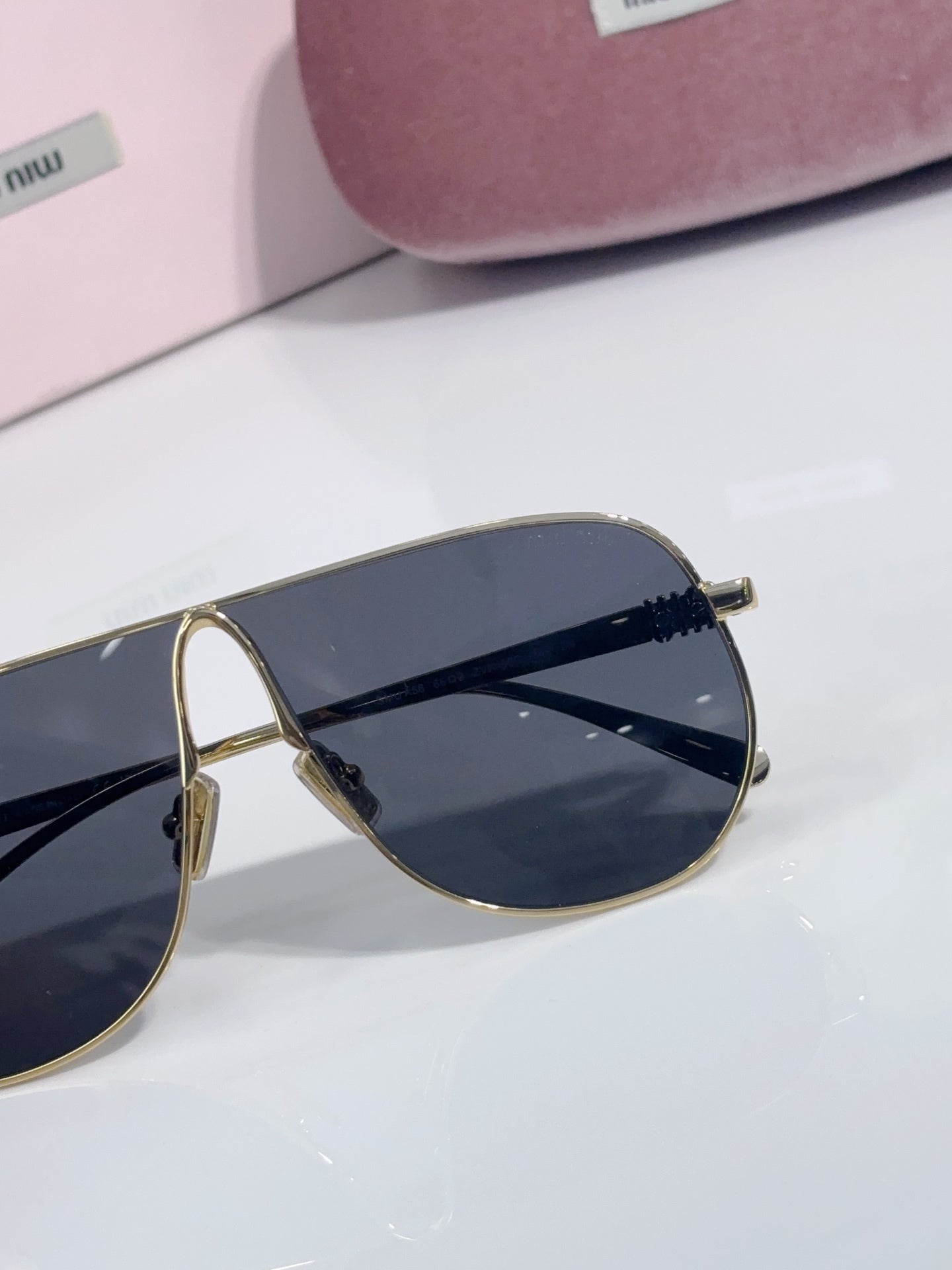 Close-up of gold-tone sunglasses frame with dark blue gradient lens