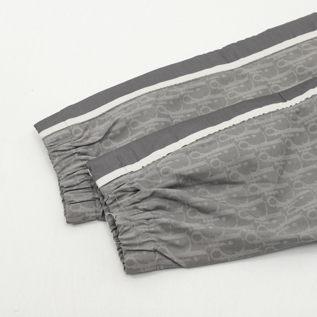 Grey Dior logo pants laid flat with elastic hem and side stripes