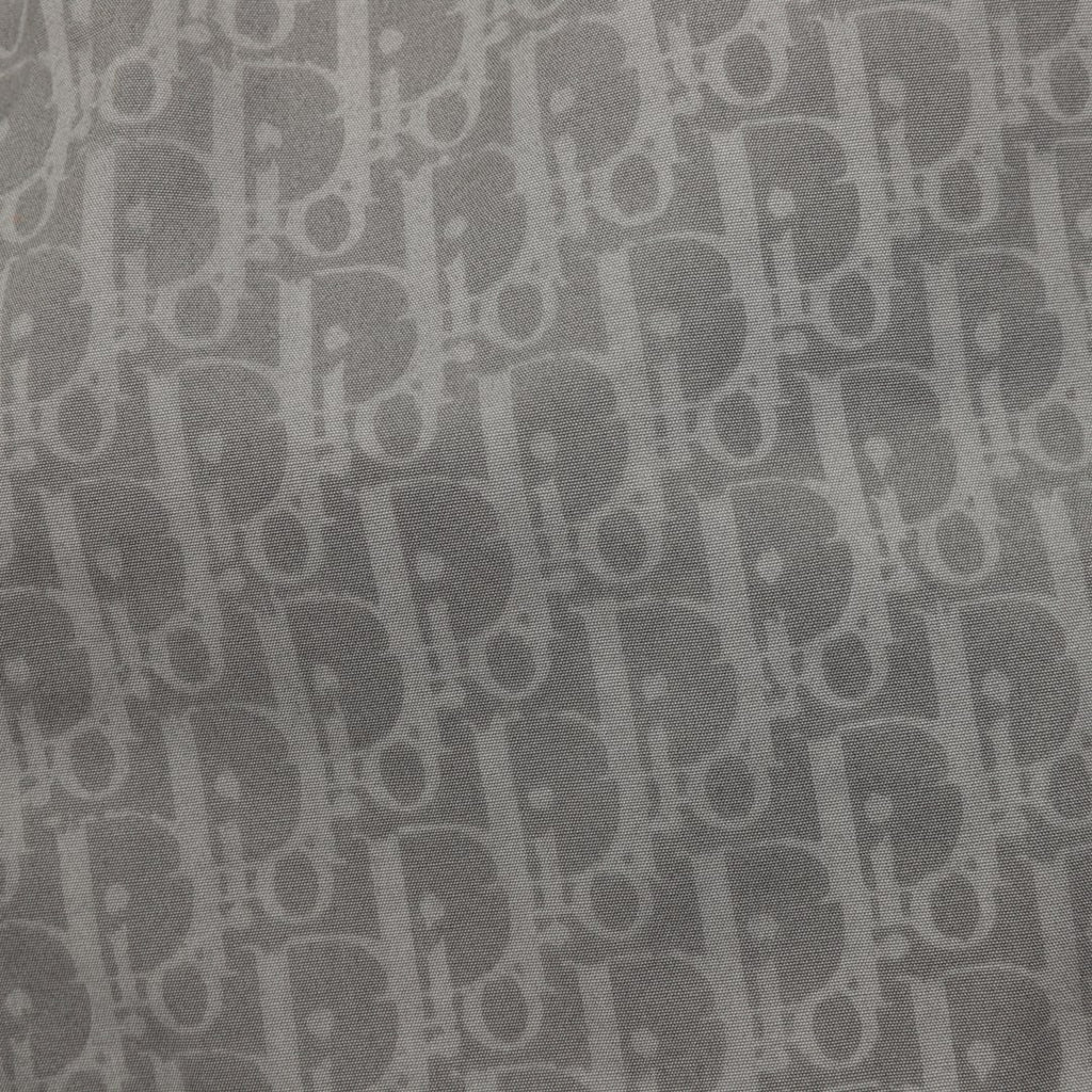 Dior pants fabric close-up showing repeating monogram pattern on dark gray