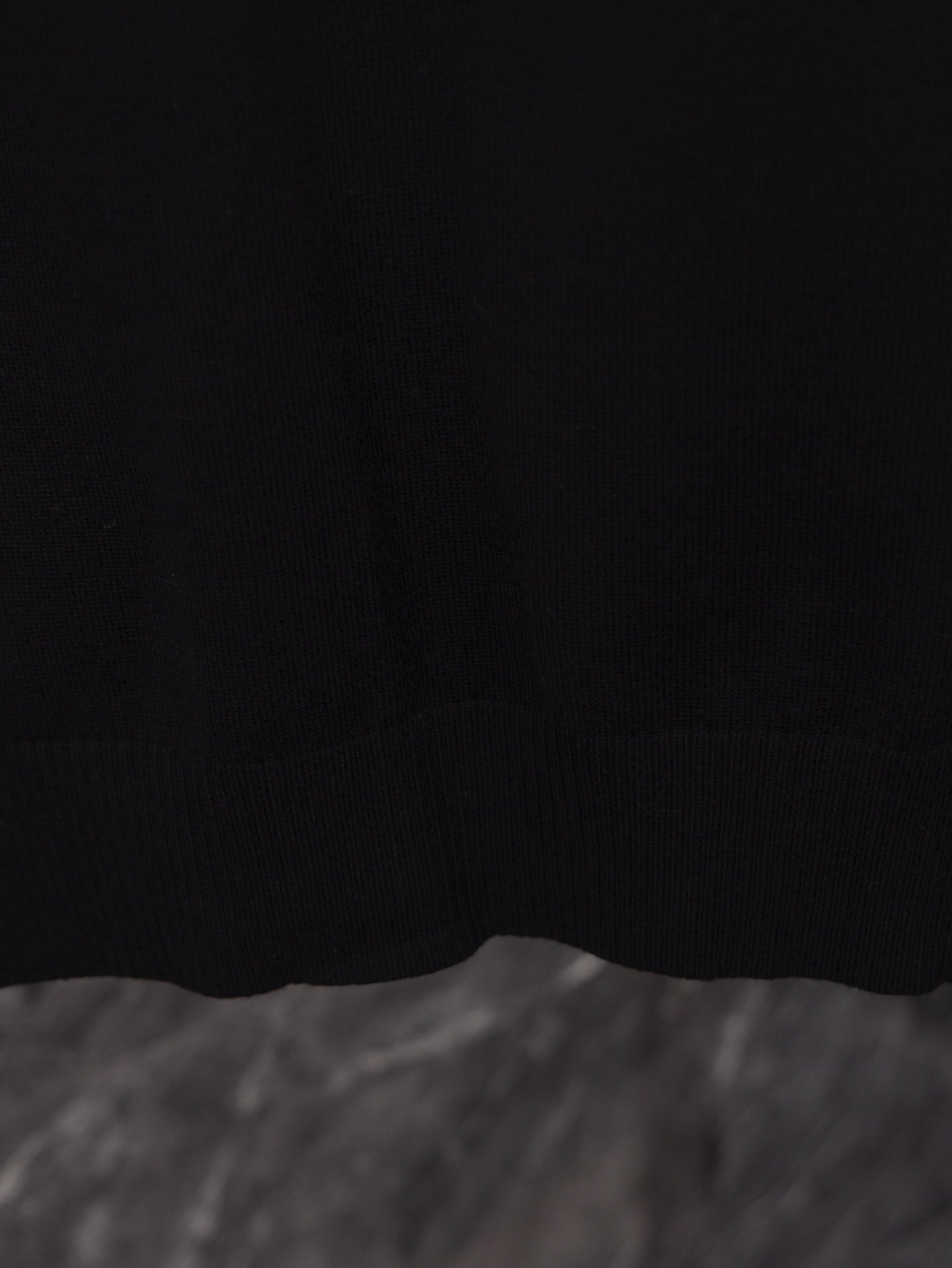 Black long-sleeve sweater hem close-up