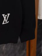 Black sweater sleeve close-up with small white “V” logo