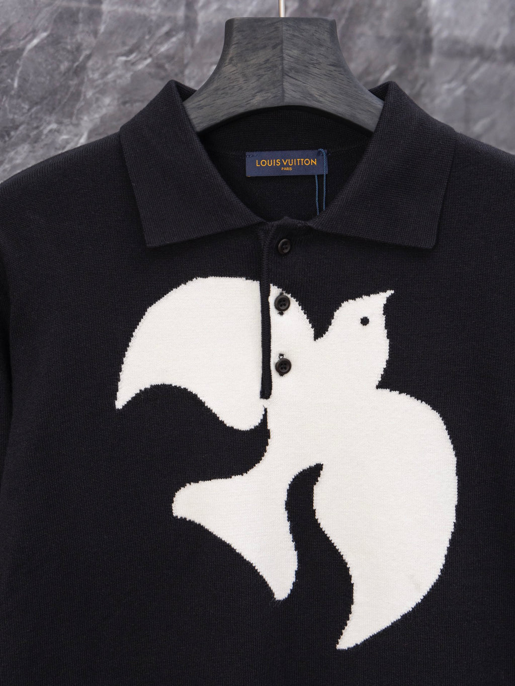 Black long-sleeve sweater with large white graphic emblem and ribbed collar