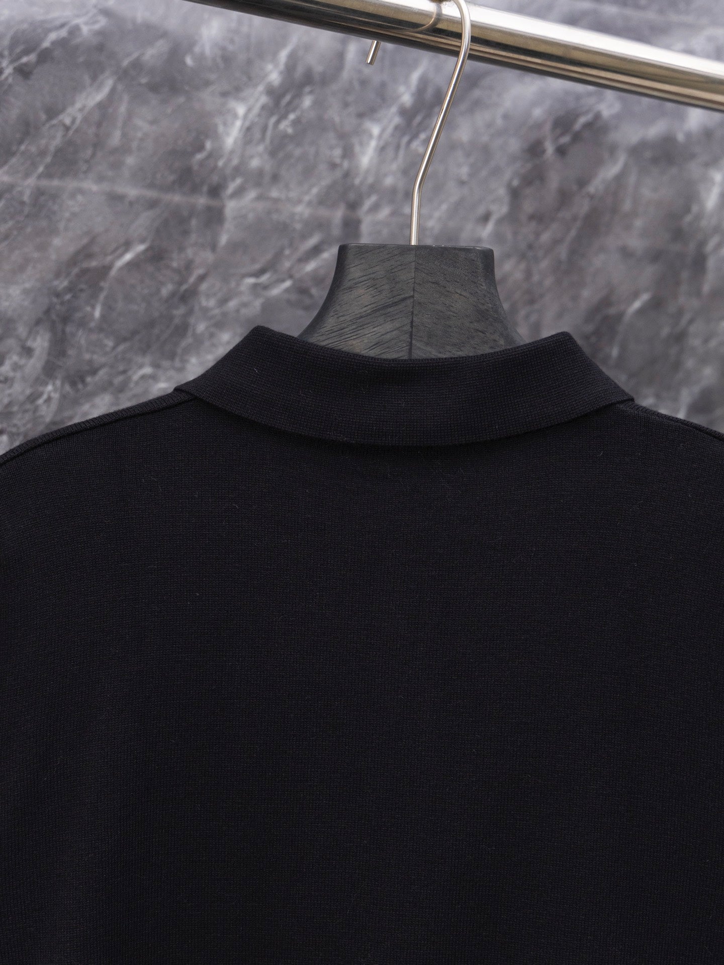 Black long-sleeve sweater top view on hanger, ribbed collar visible