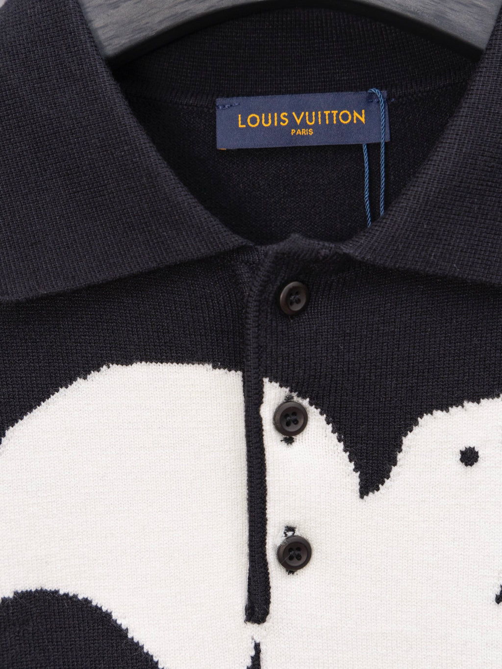 Black sweater placket close-up with buttons and white graphic print