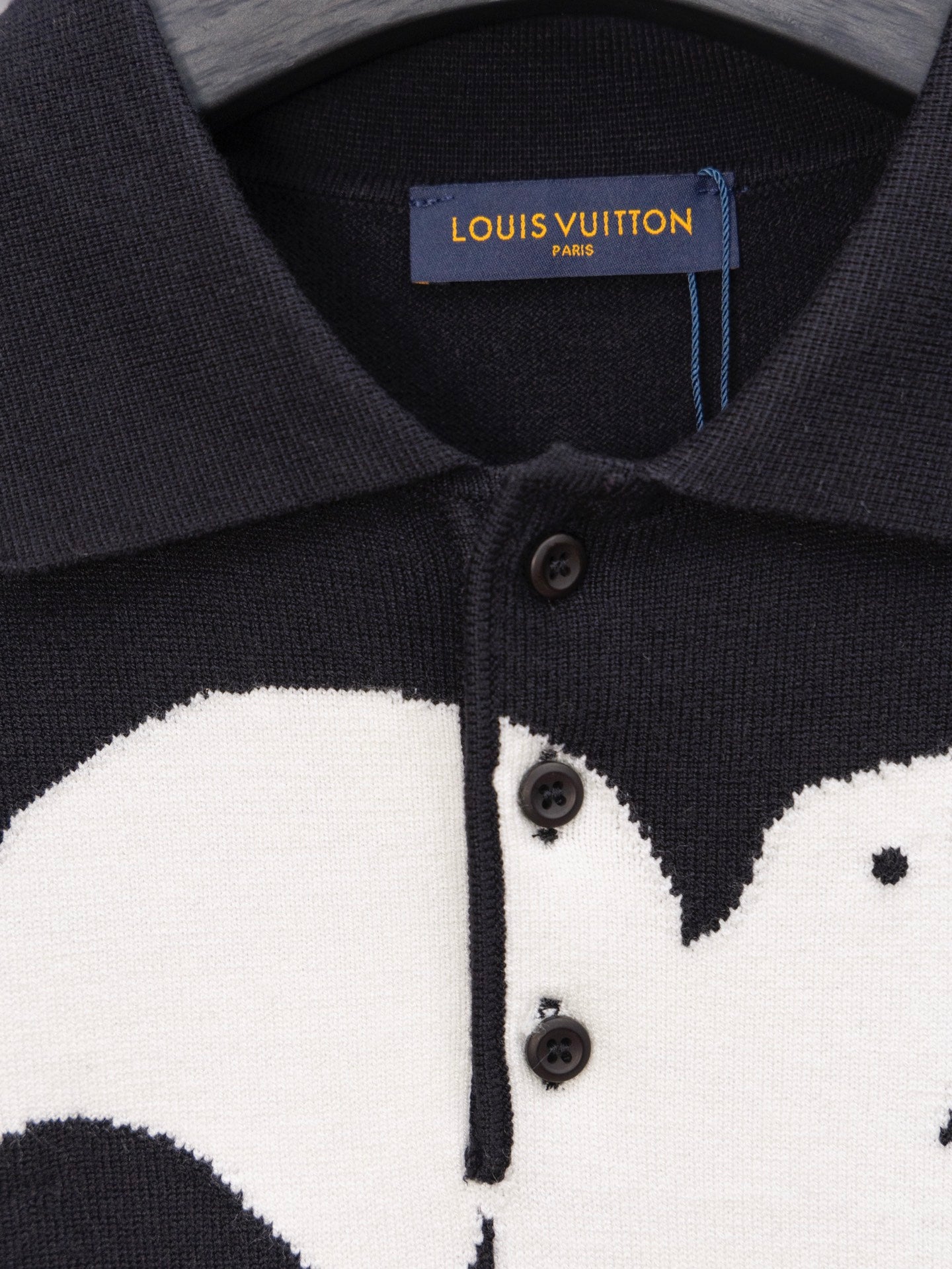 Black sweater placket close-up with buttons and white graphic print