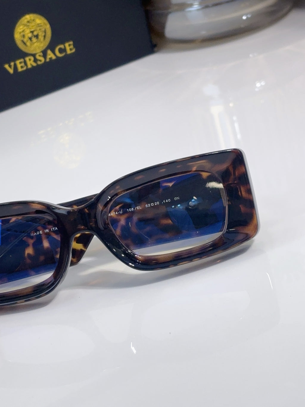 Versace cat-eye sunglasses close-up, tortoiseshell frame with blue-tinted lens