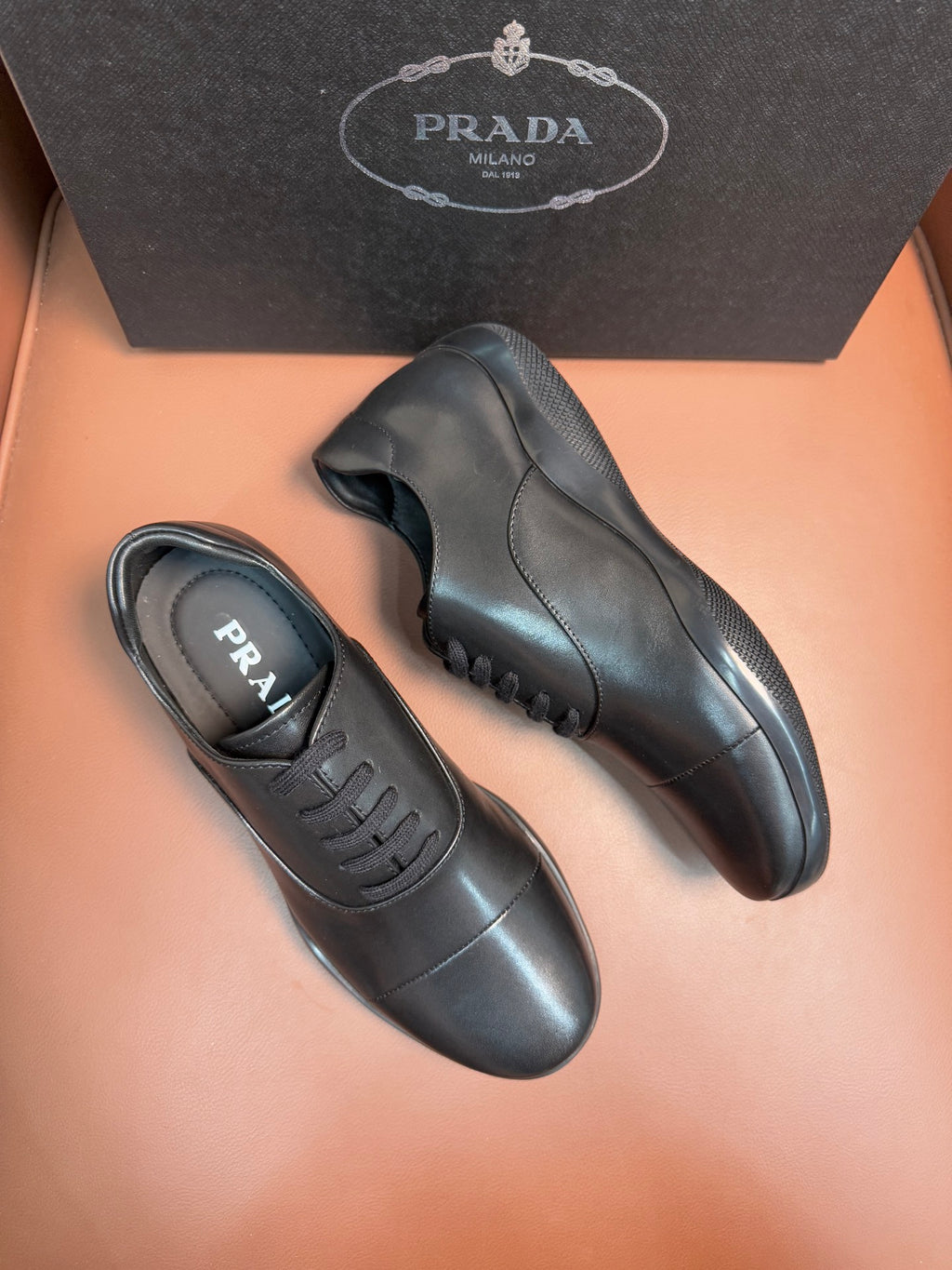Prada leather lace-up sneakers in dark blue, side view with stitched panels