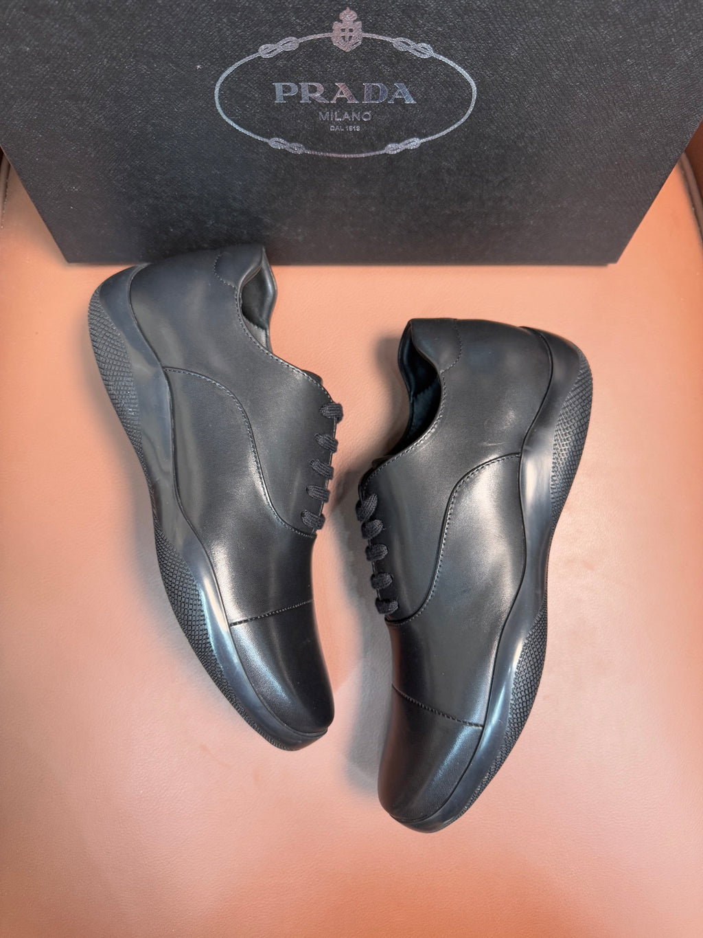 Prada leather lace-up sneakers in dark blue, angled front and side views