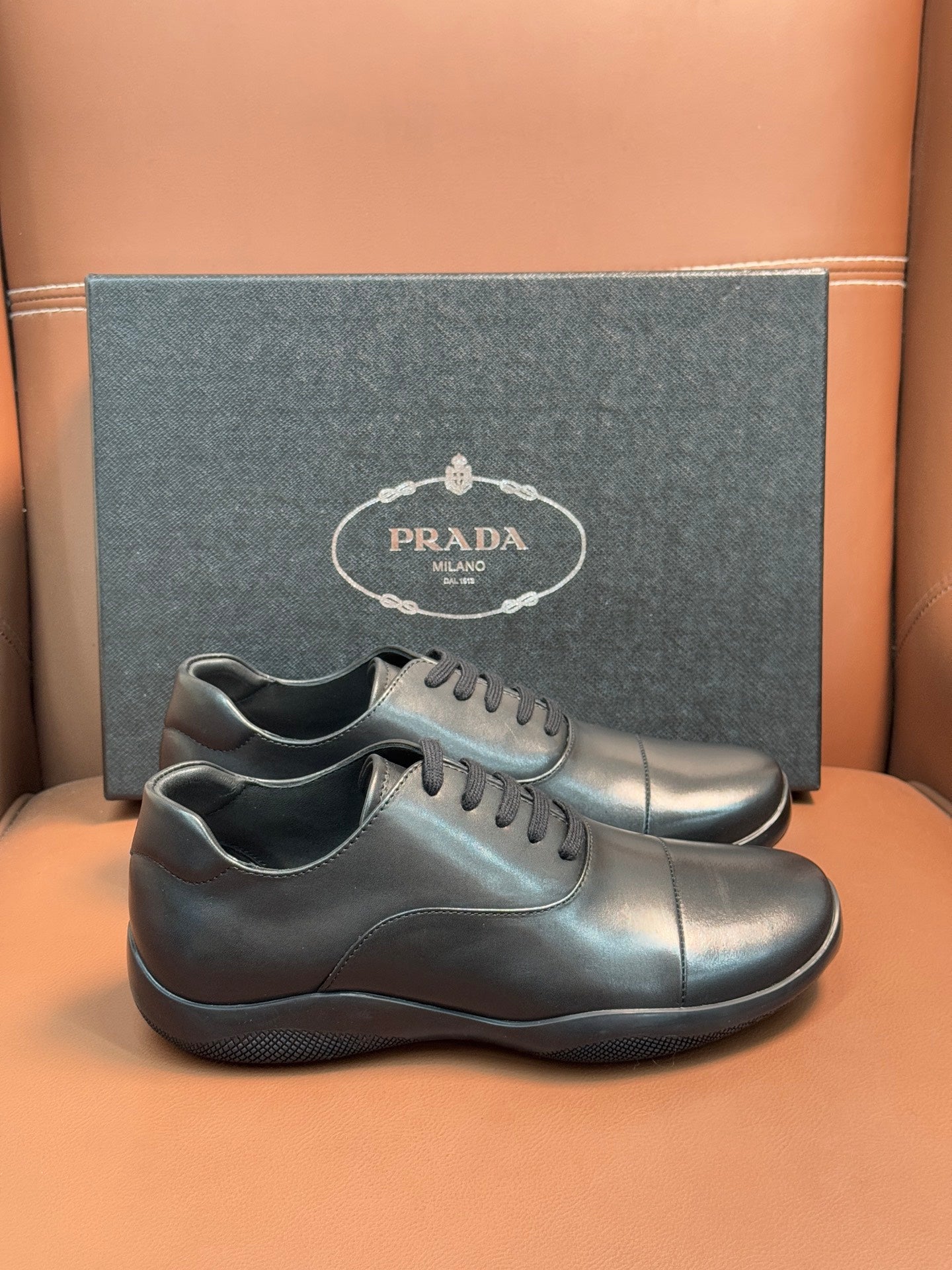 Prada leather lace-up sneakers in dark blue, front view with rounded toe