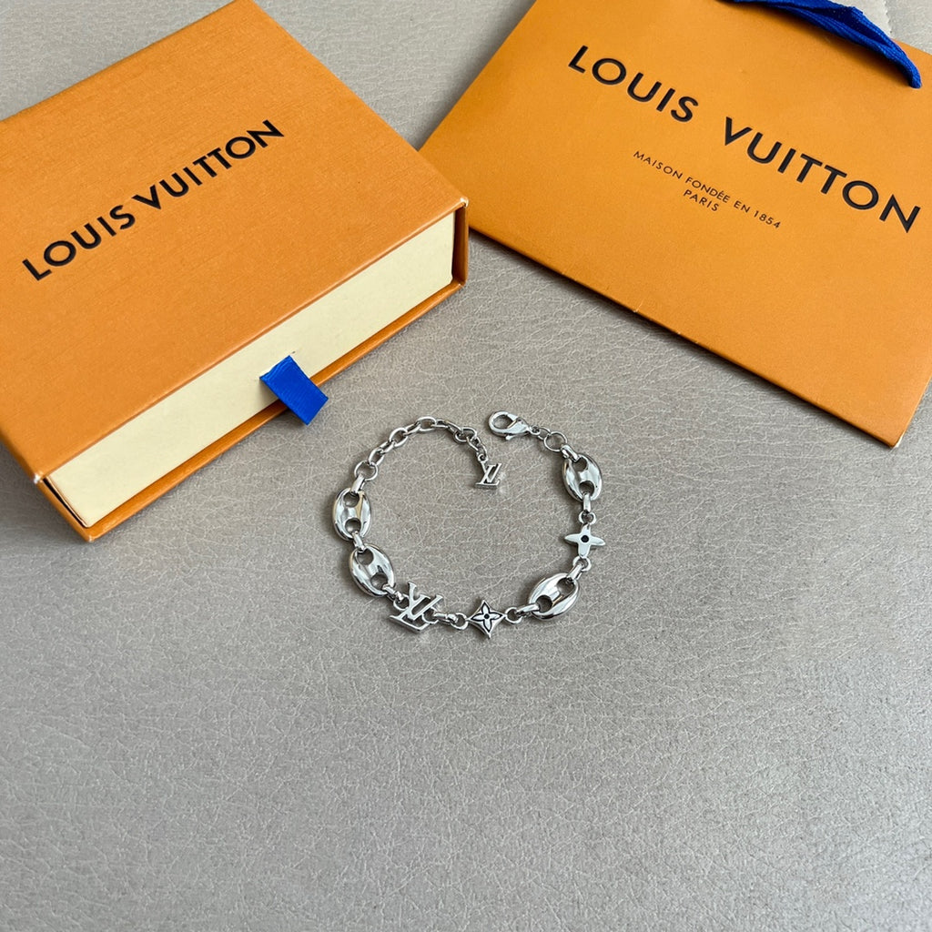 Silver charm bracelet with link chain and star, clover, and LV charms