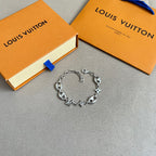 Silver charm bracelet with link chain and star, clover, and LV charms