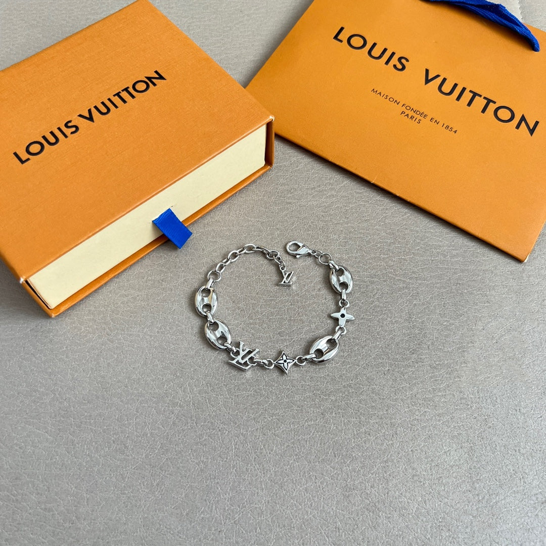 Silver charm bracelet with link chain and star, clover, and LV charms