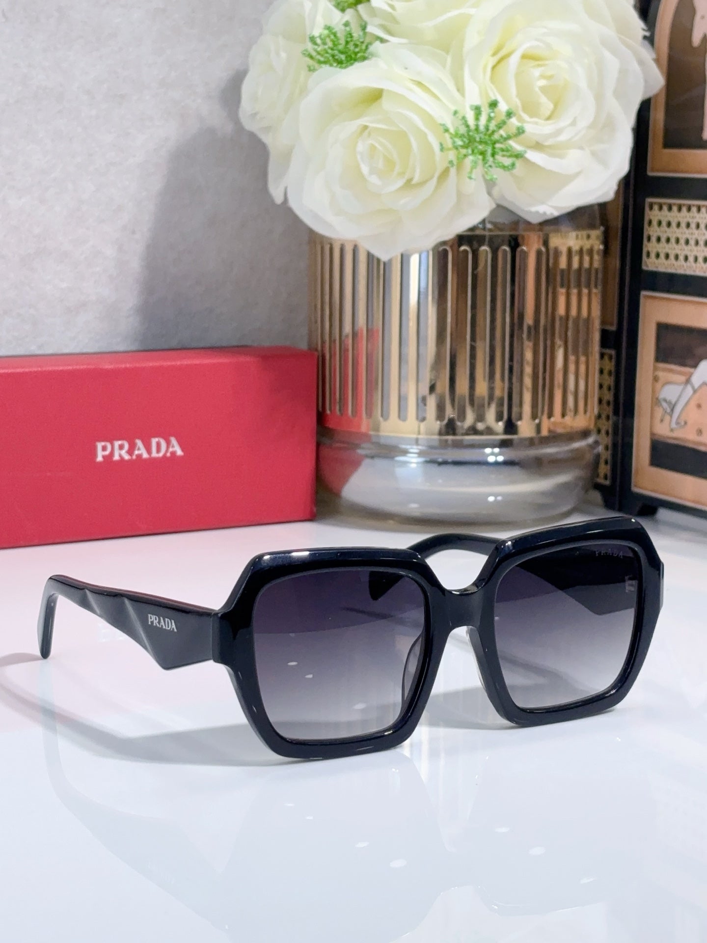 Oversized black sunglasses with dark lenses, glossy frame and Prada logo tip