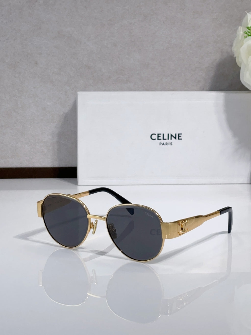 Round sunglasses with gold-tone frame, dark lenses, black accents on the temples