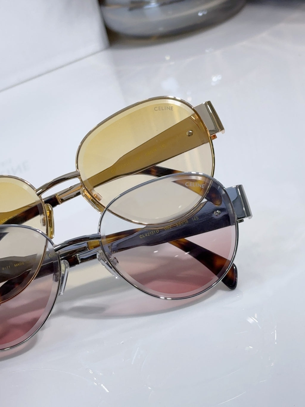 Round sunglasses close-up with gold-tone frame, overlapping lenses, tortoise temple