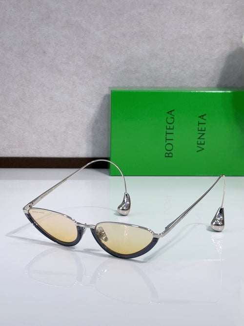 Cat-eye sunglasses with gold frame and amber lenses, pointed temple tips