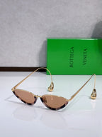 Cat-eye sunglasses with gold frame and warm brown lenses, temple detail