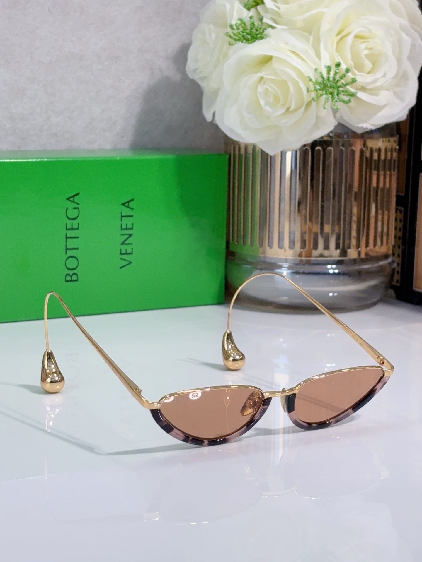 Cat-eye sunglasses with gold frame and rose-tinted lenses, angled view