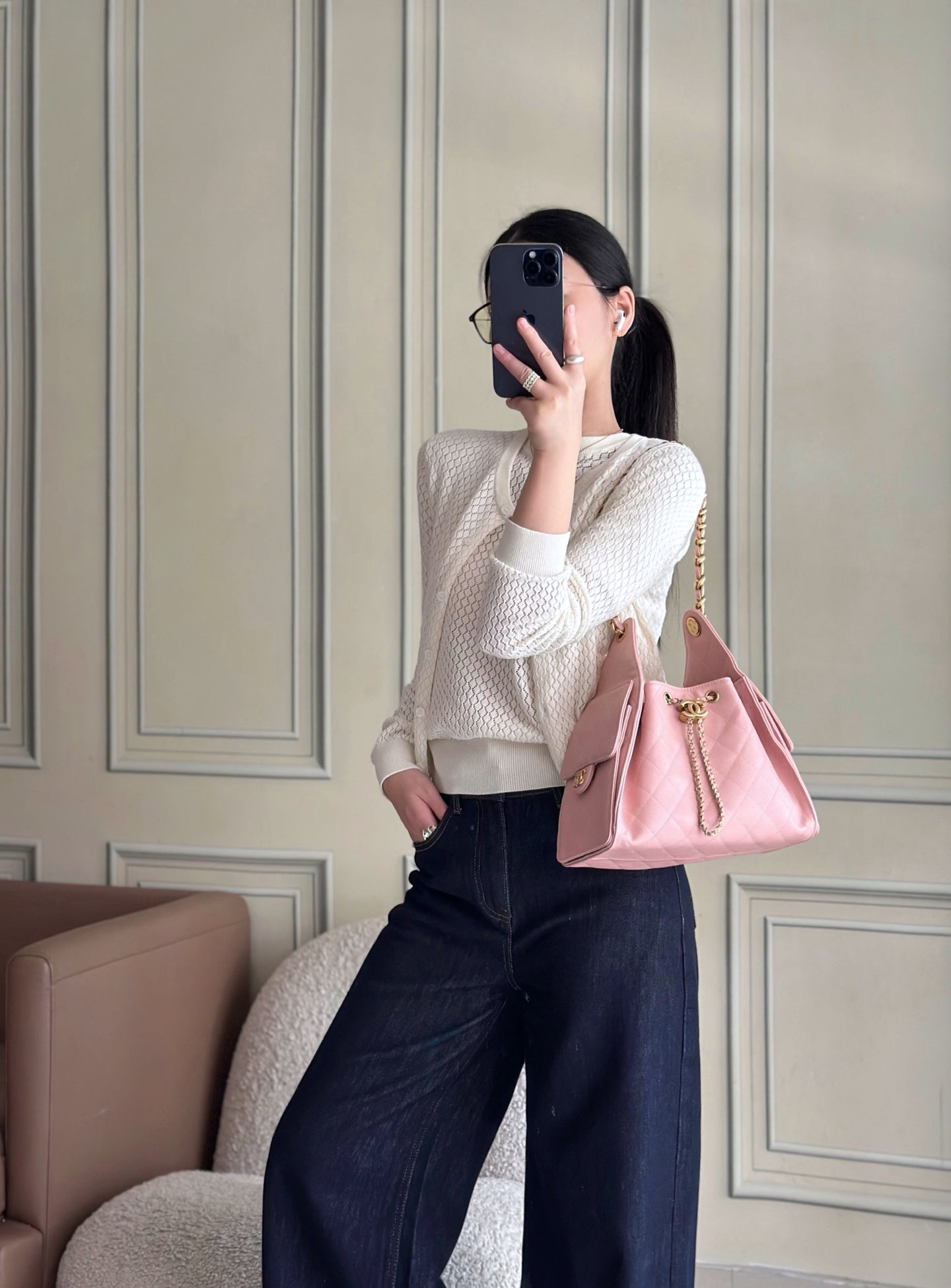 Pink Chanel mini handbag on gold chain strap, held at side by woman