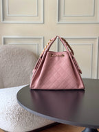 Pink quilted Chanel bucket handbag with gold chain strap, front angled view