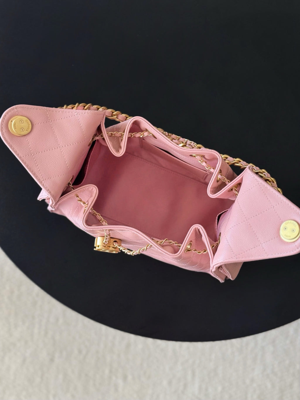 Pink Chanel quilted handbag open at top with logo snap hardware and gold chain strap