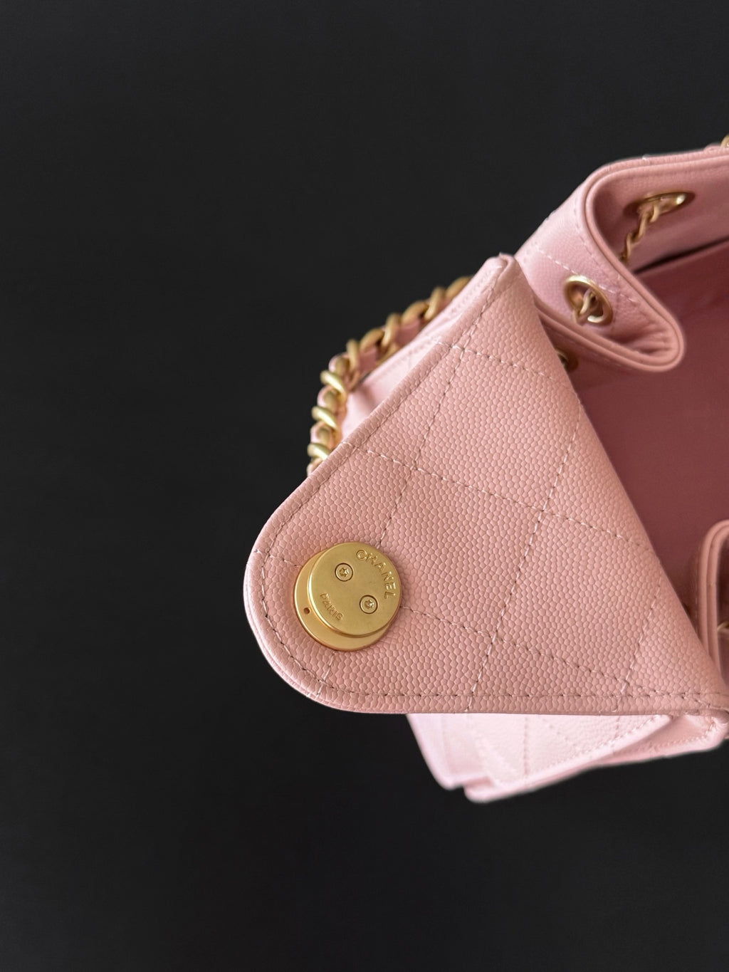 Pink Chanel handbag corner with round gold snap button and quilted leather panel