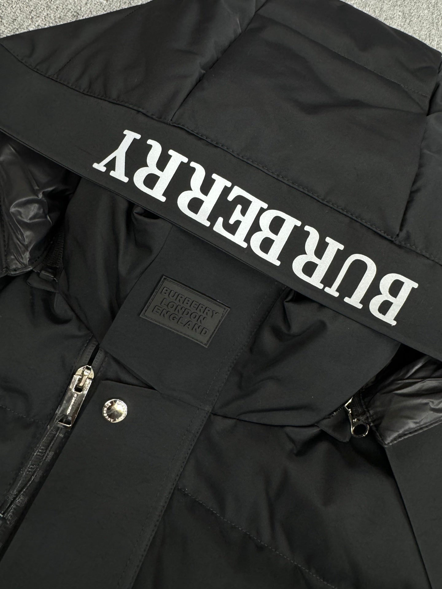 Black hooded puffer jacket hood lining with Burberry logo lettering