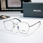 Prada glasses with silver square frames and clear lenses, dark temple arms visible.
