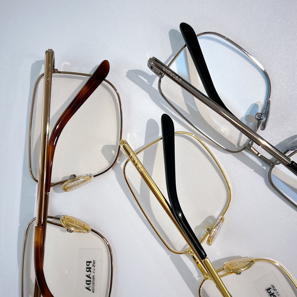Prada eyeglasses with mixed frames: red, black, and gold metal, clear lenses