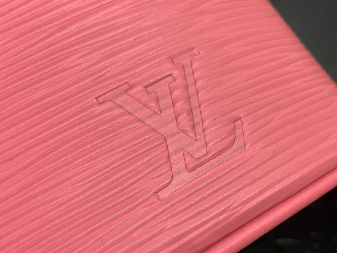 Louis Vuitton pink Epi leather close-up with embossed LV initials.