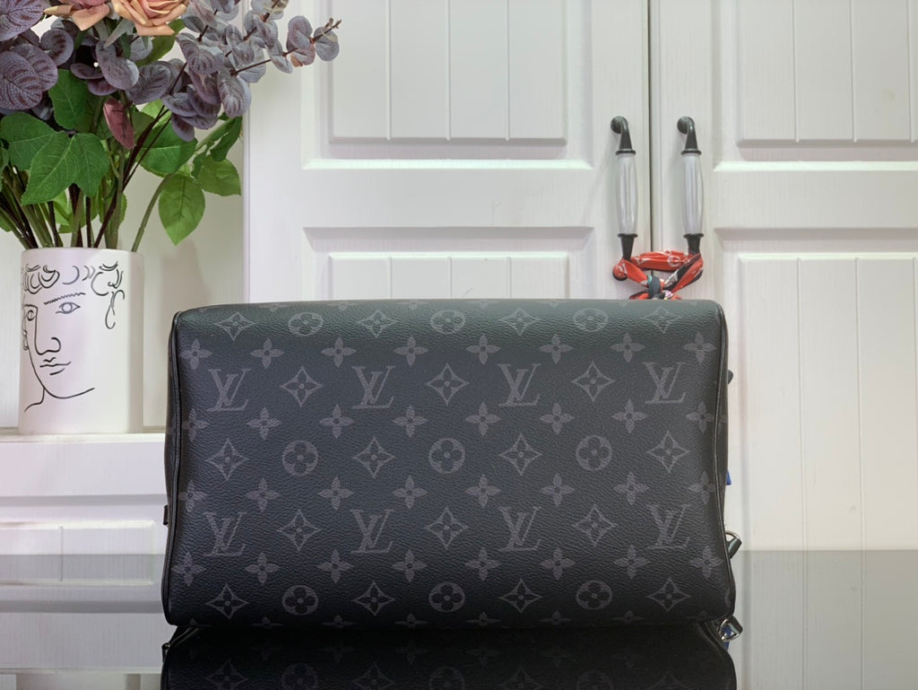 Louis Vuitton monogram handbag with structured body and dark leather trim, back view.