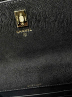 Textured black Chanel bag close-up with gold logo plate and CC charm