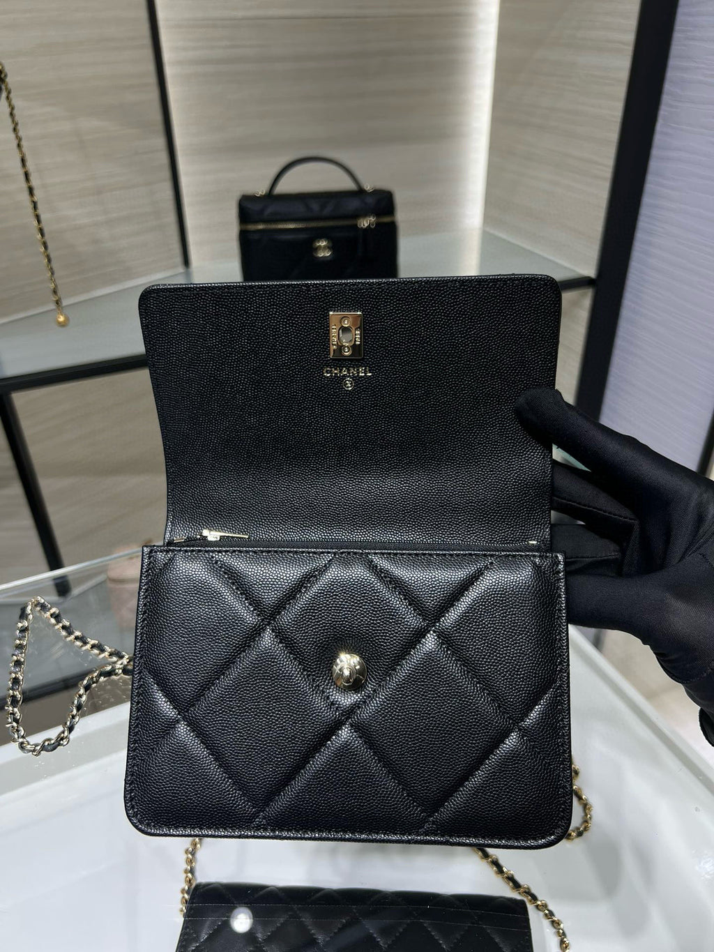 Black quilted Chanel mini bag with gold clasp, diamond stitching, and chain strap