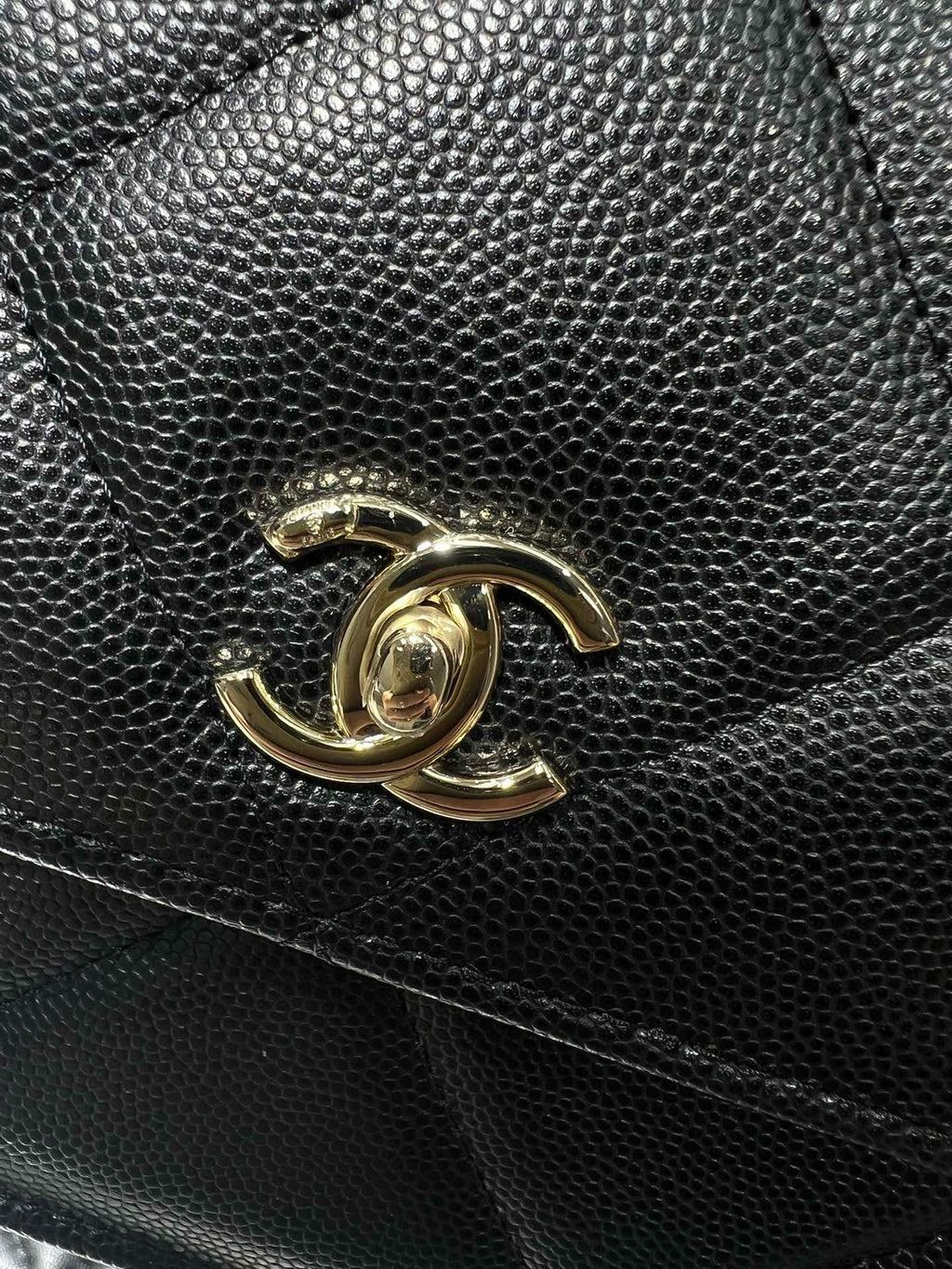 Gold Chanel CC logo on textured black leather bag front