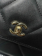 Gold Chanel CC logo on textured black leather bag front