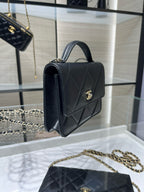 Black Chanel shoulder bag with top handle, diamond quilting, and gold CC clasp