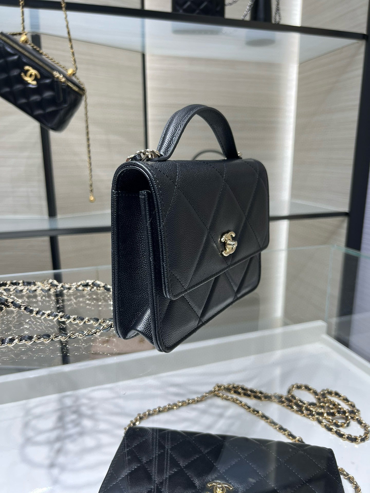 Black Chanel shoulder bag with top handle, diamond quilting, and gold CC clasp