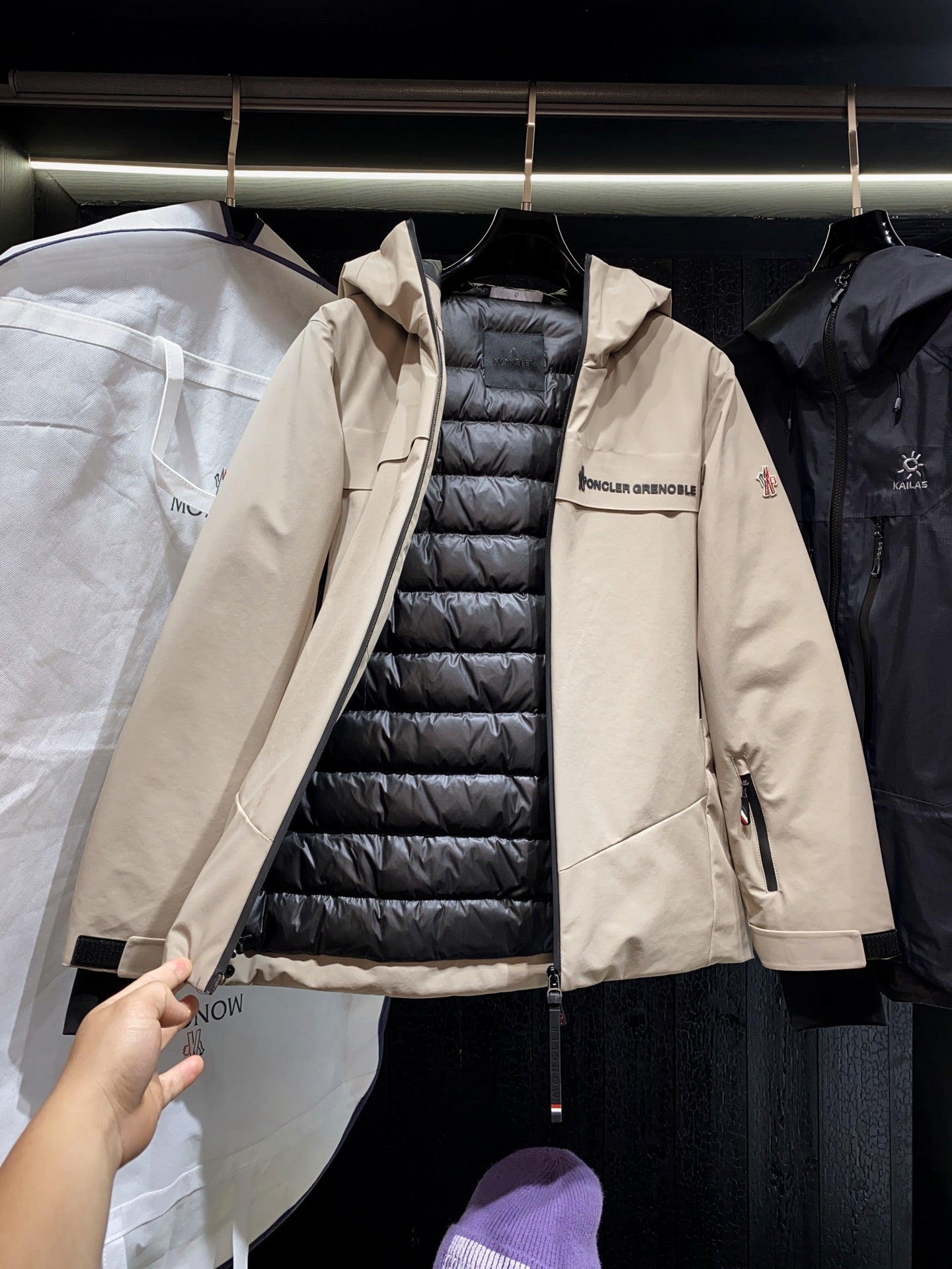 Beige long hooded jacket open, showing black puffer lining inside