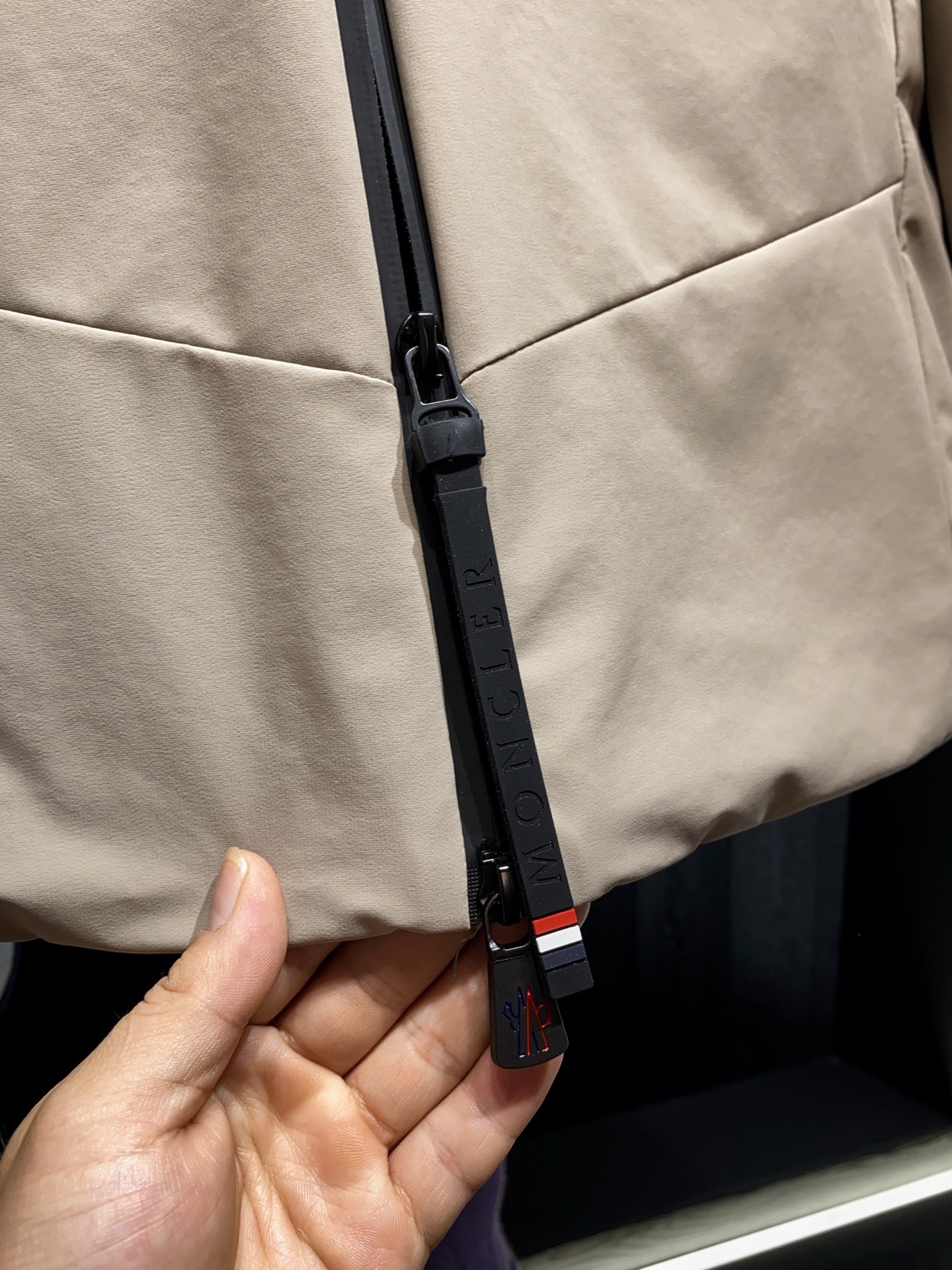 Beige jacket with black zipper pull and red-white-blue stripe tape