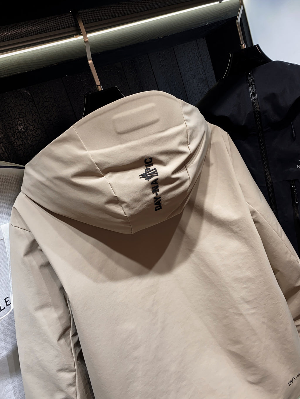 Beige hooded jacket back with printed logo text on hood