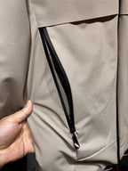 Beige zip-front jacket with black piping and angled inner pocket