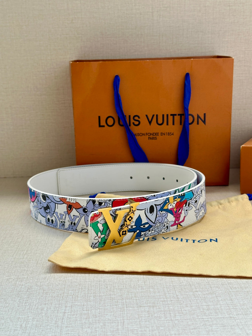Louis Vuitton belt looped on surface, white cartoon strap with metal buckle