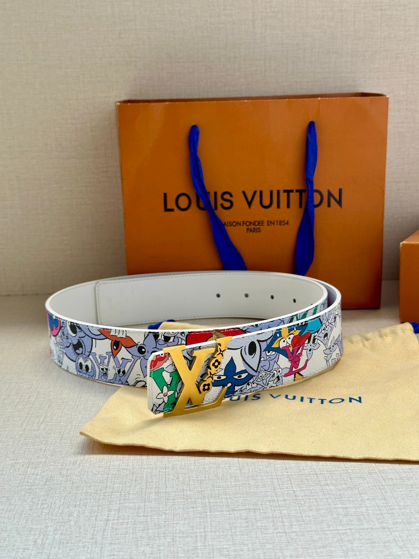 Louis Vuitton belt looped on surface, white cartoon strap with metal buckle