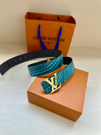 Turquoise dotted belt with gold LV buckle resting on a box
