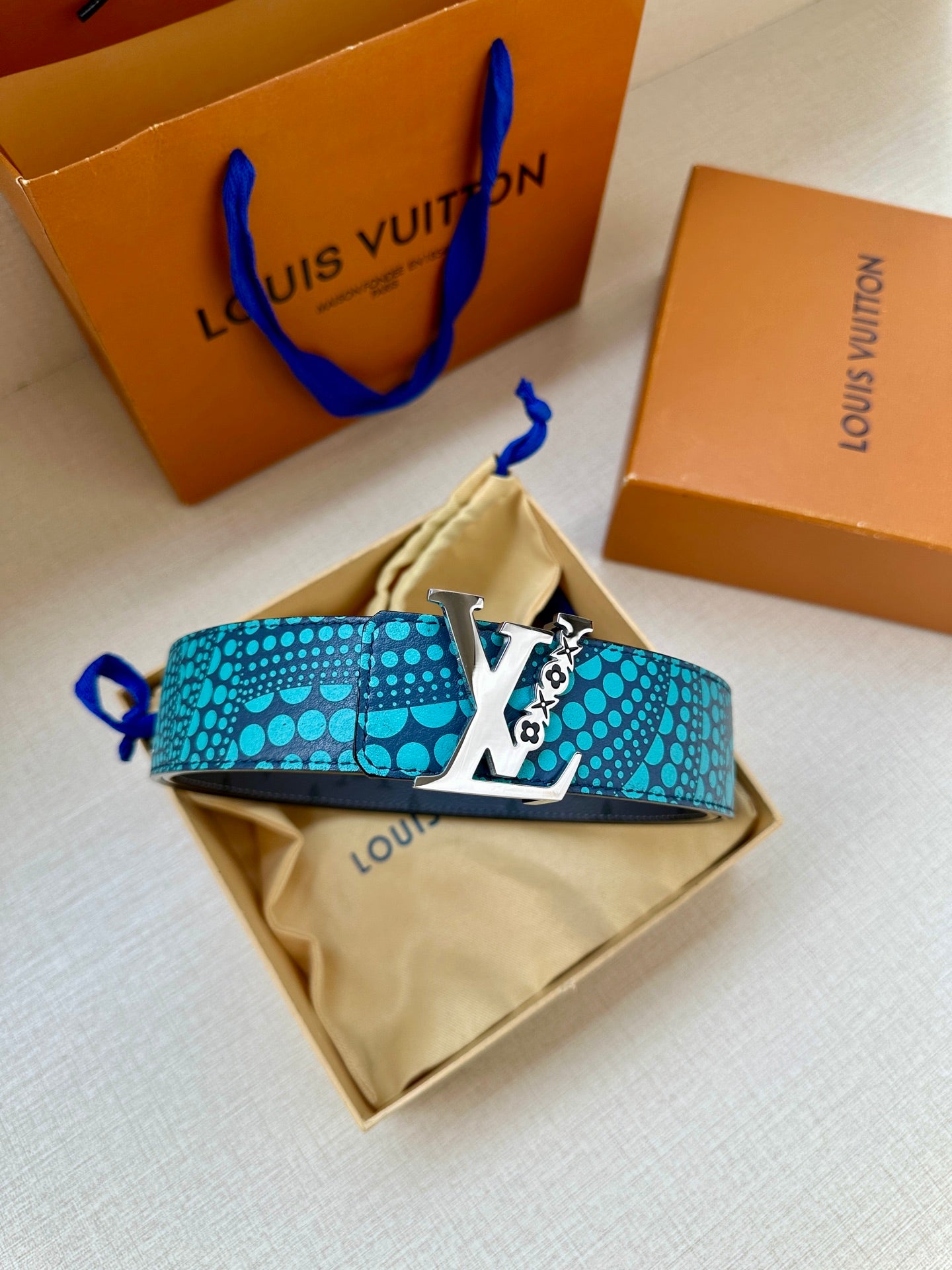 Turquoise dotted belt with gold LV buckle over a beige pouch